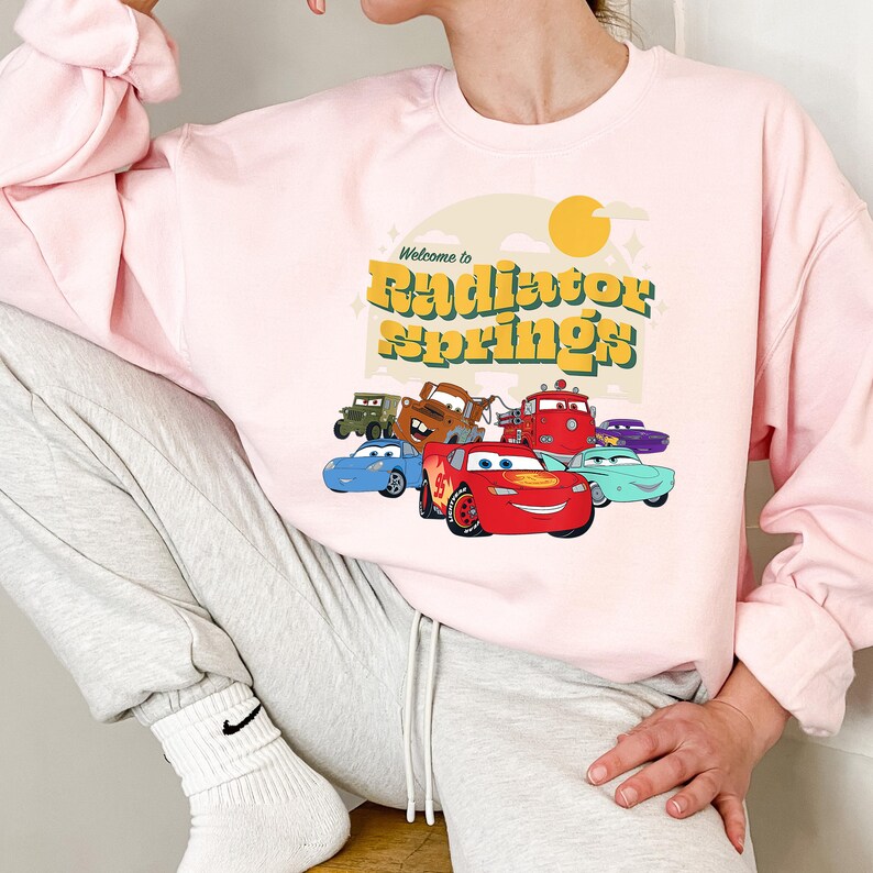 a woman wearing a pink sweatshirt with cars on it