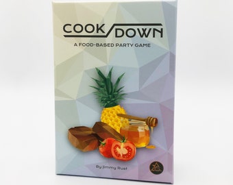 Könnte beinhalten: Eine Spielbox mit einem farbenfrohen geometrischen Muster. Die Box zeigt eine Ananas, Honig, Tomaten und Schokolade. Der Text auf der Box lautet "Cook Down: A Food-Based Party Game" und "By Jimmy Rust".