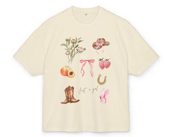 May include: A cream coloured t-shirt with a graphic design of pink flowers, a pink bow, a horseshoe, a cowboy hat, peaches, strawberries, and cowboy boots. The text "Just a girl!" is printed on the shirt.
