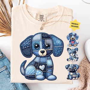 May include: Cream-colored t-shirt featuring a patchwork-style blue dog graphic with a heart. Additional small dog illustrations are included. The shirt is paired with blue jeans and a beige sweater.