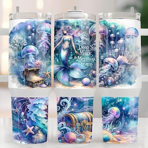 May include: A set of three stainless steel tumblers with a watercolor design of a mermaid, jellyfish, and a treasure chest. The tumblers have a white background with blue, purple, and pink accents. The text "Deep Sea Magic & Mermaid Dreams" is printed on the middle tumbler.