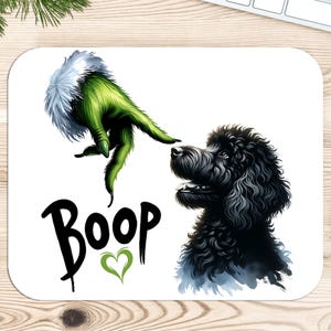 K&ouml;nnte beinhalten: Eine wei&szlig;e Mausmatte mit einer gr&uuml;nen Grinch-Hand, die sich nach einem schwarzen Pudel ausstreckt. Der Text "Boop" ist in Schwarz mit einem gr&uuml;nen Herzen darunter geschrieben.