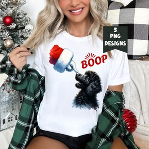 K&ouml;nnte beinhalten: Ein wei&szlig;es T-Shirt mit einem schwarzen Pudel und einer Weihnachtsmann-Hand, die auf den Hund zeigt. Der Text "BOOP" befindet sich &uuml;ber dem Hund.