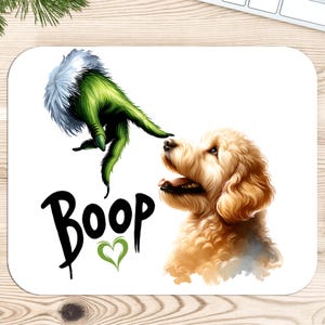 K&ouml;nnte beinhalten: Eine wei&szlig;e Mausmatte mit einer gr&uuml;nen Grinch-Hand, die sich nach einem Golden Retriever-Hund ausstreckt, um ihn zu "boop"en. Der Text "Boop" ist in Schwarz mit einem gr&uuml;nen Herzen geschrieben.
