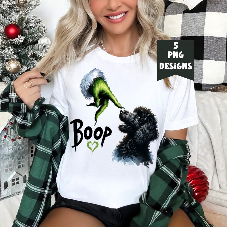 K&ouml;nnte beinhalten: Wei&szlig;es T-Shirt mit einer gr&uuml;nen Grinch-Hand, die sich nach einem schwarzen Pudel mit dem Text "Boop" und einem gr&uuml;nen Herzen ausstreckt.