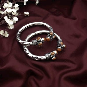 May include: A white ceramic mug with a black handle and the text "But First, Coffee" in a bold, black font. The mug is sitting on a wooden surface. The mug appears to be 12 ounces.