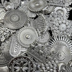 May include: A collection of silver-toned metal charms with intricate designs, including circles, flowers, and geometric patterns. The charms are arranged on a black background.