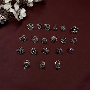 Pu&ograve; includere: Un set di 18 anelli per il naso in argento con vari design, tra cui fiori, pavoni e forme geometriche.