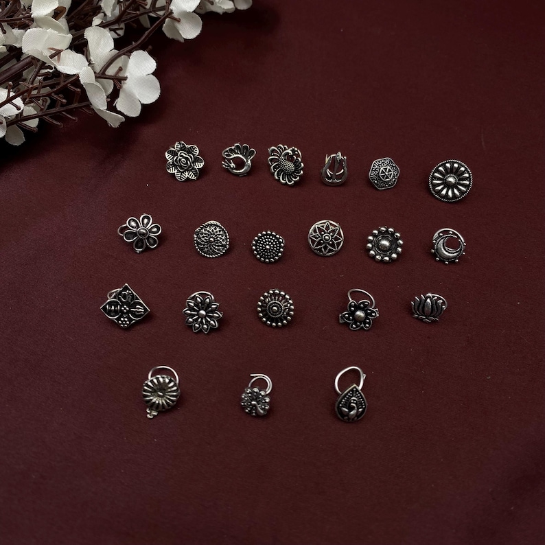 Pu&ograve; includere: Un set di 18 anelli per il naso in argento con vari design, tra cui fiori, pavoni e forme geometriche.