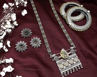 May include: A long necklace with alternating gold and silver beads, featuring a rectangular pendant with a gold peacock motif and four circular textured discs. The set includes two round floral stud earrings and two silver bangles with spiked edges.