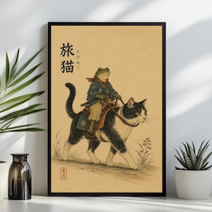 May include: A framed art print on a tan background featuring a green frog dressed in a blue patterned kimono riding a black and white cat. The cat wears a saddle with a floral design. Japanese text is visible in the upper left and lower left.