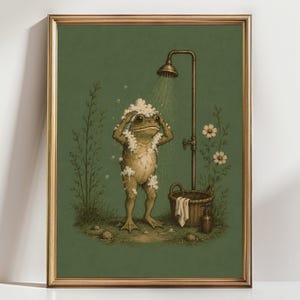 May include: A framed wall art print featuring a green frog standing under a vintage-style shower head. The frog is covered in white soap suds, with a woven basket, a white towel, and a small bottle nearby, all set against a muted green background.