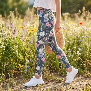 May include: High-waisted leggings featuring a dark blue base with a vibrant, multi-colored floral print of pink, white, and blue flowers and green foliage, paired with a white short-sleeved top and white athletic sneakers.