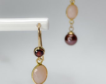 May include: A pair of gold earrings with a pink stone, a red stone, and a brown pearl on each earring.