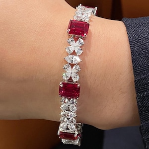 May include: A dazzling bracelet featuring alternating rectangular red gemstones and clusters of white, sparkling stones. The bracelet is set in a silver or white metal, creating a luxurious and eye-catching accessory.