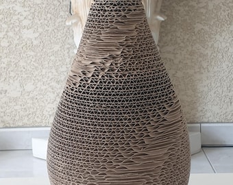 May include: A brown cardboard vase with a unique, textured, honeycomb-like design. The vase is shaped like a teardrop and has a wide opening at the top.
