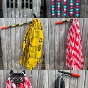 May include: A set of six different colorful noisemakers. The noisemakers are made of plastic and have a variety of shapes and sizes. They are hung on a wooden wall with a black and orange string. The noisemakers are a fun and festive way to add some noise to any party or celebration.