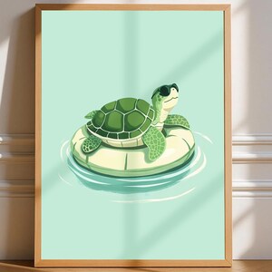 May include: A framed art print depicting a cartoon turtle wearing sunglasses, floating on a yellow and white inflatable ring in water. The turtle has a green, patterned shell. The background is a light teal colour.