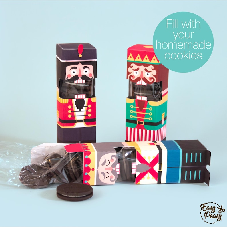 May include: Nutcracker-themed cookie boxes in red, green, and blue. The boxes are filled with cookies and are decorated with nutcracker faces and uniforms. The text "Fill with your homemade cookies" is in a teal circle.