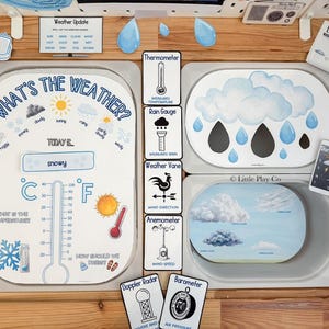 May include: A children's weather learning set with various illustrated cards and a central display. The set includes cards for weather updates, temperature, rain gauge, and wind direction. The main display shows "What's the Weather?" and "Today: snowy."