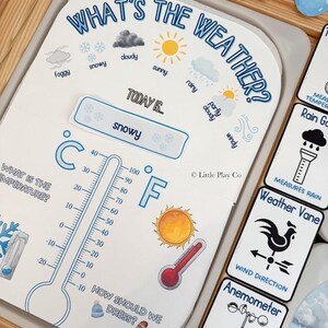 May include: A weather-themed educational set with cards and a thermometer. The main card reads "What's the Weather?" and includes weather condition illustrations like snowy, sunny, and cloudy. A thermometer displays Fahrenheit and Celsius scales. Additional cards show weather instruments.