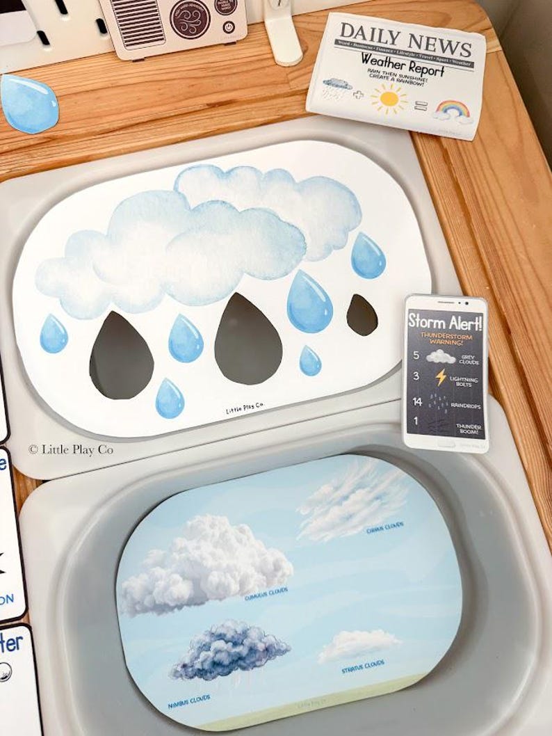 May include: Two oval educational activity mats featuring weather themes. The top mat displays watercolor clouds and raindrops with a Storm Alert card. The bottom mat illustrates various cloud types labeled Cirrus, Cumulus, Stratus, and Nimbus.