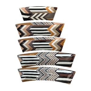 May include: A stack of five rectangular serving dishes. Each dish features a geometric pattern with brown, black, white, and tan chevron and striped designs. The dishes are arranged vertically against a white background.