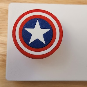 May include: A 3D printed Captain America shield, featuring red, white and blue colours with a white star in the centre.