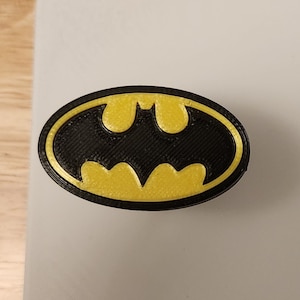 May include: A black and yellow 3D printed Batman logo.