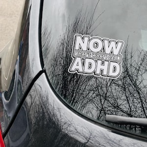May include: A white vinyl decal with a black border applied to a car window. The text reads NOW THAT'S WHAT I CALL ADHD in a bold, stacked, sans-serif font style. The design features a clean, high-contrast aesthetic with clear, legible lettering.
