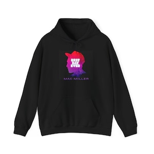 Op de afbeelding: Zwarte hoodie met een grafische print op de voorkant. De print toont een silhouet van een persoon met een hoed, met de woorden "BEST DAY EVER" en "MAC MILLER" in rode, paarse en blauwe verlopen.
