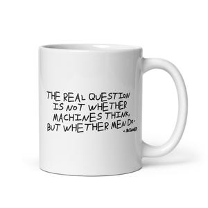 May include: A white ceramic mug featuring black handwritten-style text that reads: The real question is not whether machines think, but whether men do. - Skinner. The mug has a standard cylindrical shape with a curved handle on the right side.