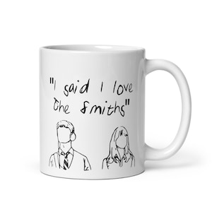 May include: White ceramic mug with a black line drawing of a man and woman. The mug has the text "I said I love the Smiths" printed on it.