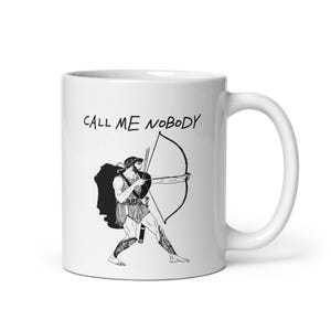Puede incluir: Una taza de cerámica blanca con una ilustración de líneas negras de un arquero antiguo apuntando con arco y flecha. Sobre la figura, el texto CALL ME NOBODY está impreso en una fuente sencilla de estilo dibujado a mano.