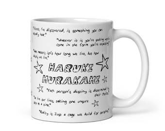 May include: White ceramic mug with black text and star designs. The text includes quotes from Haruki Murakami, including "Silence, I've discovered, is something you can actually hear!" and "Reality is just a cage we build for ourselves."