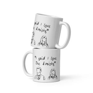 May include: Two white ceramic mugs stacked on top of each other. The top mug has the text "gaid I love he Smiths" written on it. The bottom mug has the text "I said I love The Smiths" written on it.