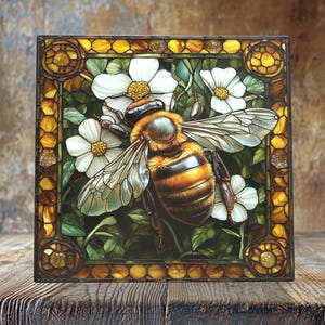 May include: A square stained glass panel featuring a detailed bee with translucent wings, set against white flowers and green foliage. The bee has brown and yellow stripes. The panel is framed with a decorative border of amber and gold tones.