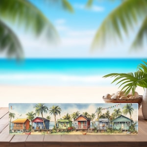 May include: A colorful painting of beach houses with palm trees and a blue sky. The houses are painted in shades of blue, green, red, and yellow. The painting is framed and ready to hang.