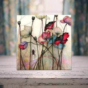 May include: A square art print featuring a botanical illustration of poppies in shades of red, pink, and white. Thin red lines connect the flowers and seed pods, resembling thread. A small black spider is positioned among the stems and petals.