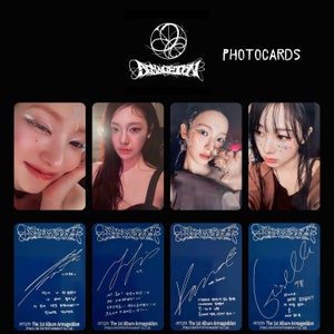 Puede incluir: Un conjunto de fototarjetas K-pop con cuatro retratos de un artista musical. La palabra "PHOTOCARDS" está en blanco en la parte superior. La fila inferior muestra tarjetas azules con firmas y texto. El título del álbum "Armageddon" es visible.