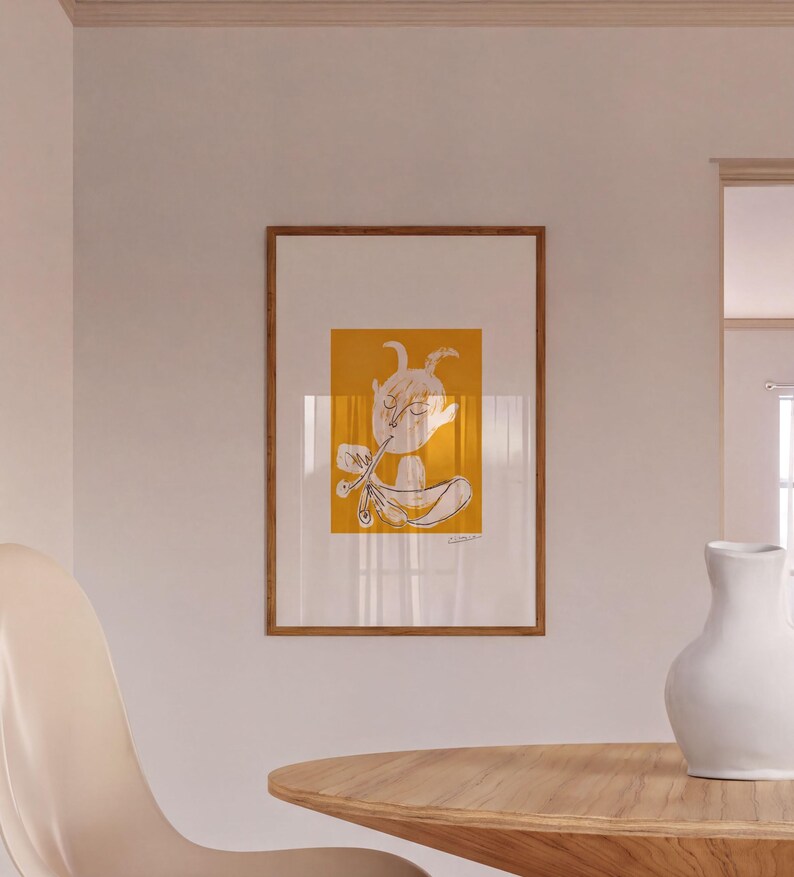 a wooden table with a white vase on it, and a framed artwork hanging on the wall above the table.