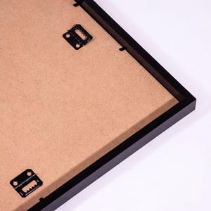 a black frame with a brown paper inside, placed on a white surface.
