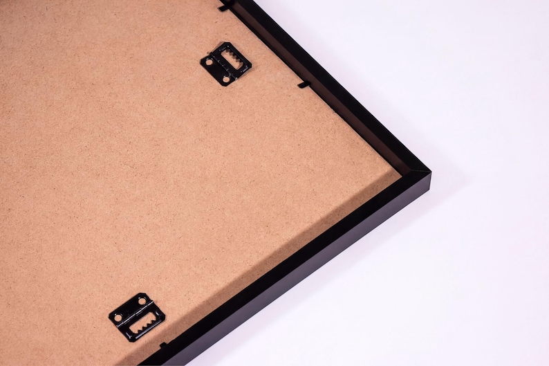 a black frame with a brown paper inside, placed on a white surface.