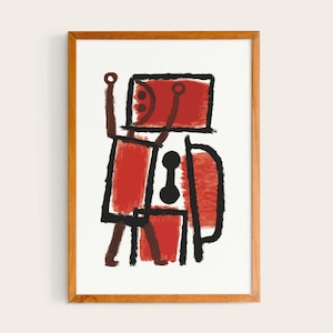 Puede incluir: Impresión artística abstracta en un marco de madera. La obra presenta una figura roja con contornos y detalles negros, sobre un fondo blanco. La figura tiene una cabeza rectangular y los brazos levantados. El marco es de color marrón cálido.