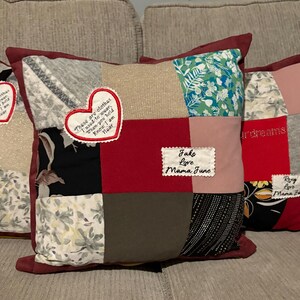 Pode incluir: Uma almofada de patchwork com uma borda bord&ocirc;. A almofada apresenta quadrados de v&aacute;rios tecidos em cores como cinza, vermelho e estampas florais. Patches bordados incluem o texto "These are clothes I used to wear..." e "Jake Love Mama June."