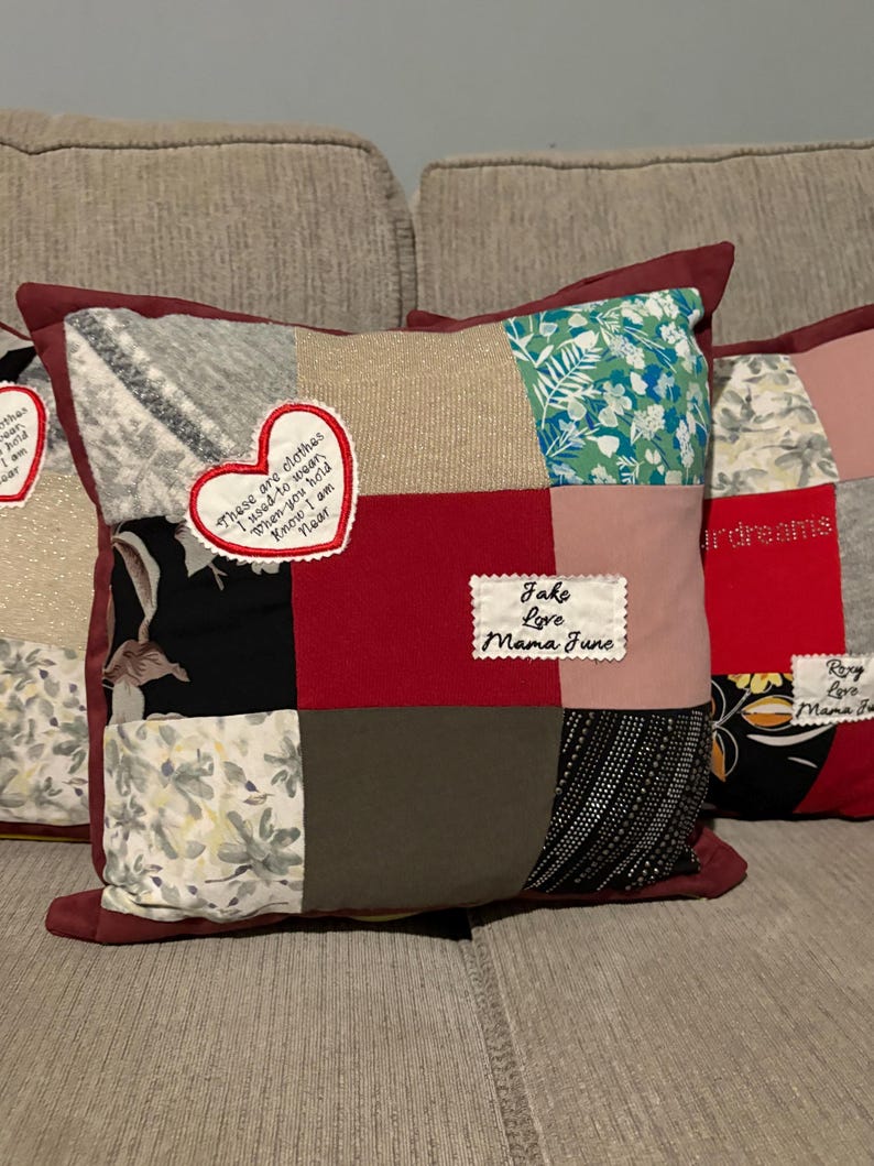 Pode incluir: Uma almofada de patchwork com uma borda bord&ocirc;. A almofada apresenta quadrados de v&aacute;rios tecidos em cores como cinza, vermelho e estampas florais. Patches bordados incluem o texto "These are clothes I used to wear..." e "Jake Love Mama June."