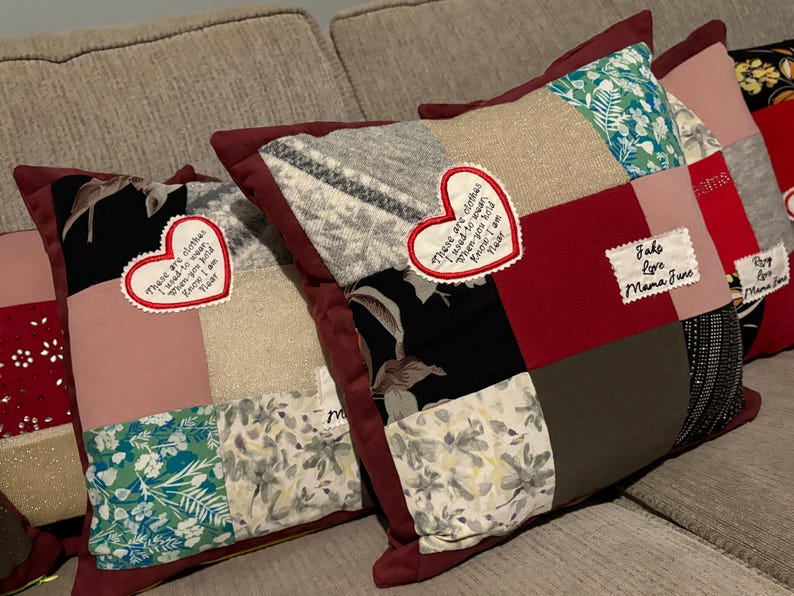 Pode incluir: Uma cole&ccedil;&atilde;o de almofadas de patchwork com bordas bord&ocirc;. Cada almofada apresenta uma variedade de quadrados de tecido em cores como vermelho, rosa, preto e estampas florais. Patches em forma de cora&ccedil;&atilde;o com texto bordado s&atilde;o vis&iacute;veis em algumas almofadas.