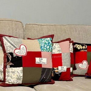 Pode incluir: Um conjunto de almofadas de patchwork com uma borda bord&ocirc;. Cada almofada apresenta uma variedade de quadrados de tecido em padr&otilde;es vermelhos, cinza, preto e florais. Algumas almofadas t&ecirc;m apliques em forma de cora&ccedil;&atilde;o com texto.