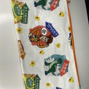 May include: White zippered pouch with a repeating pattern of Toy Story characters, including Woody, Rex, and the Aliens. The characters are depicted in a vintage style with text that reads "Woody", "Rex", and "Aliens".