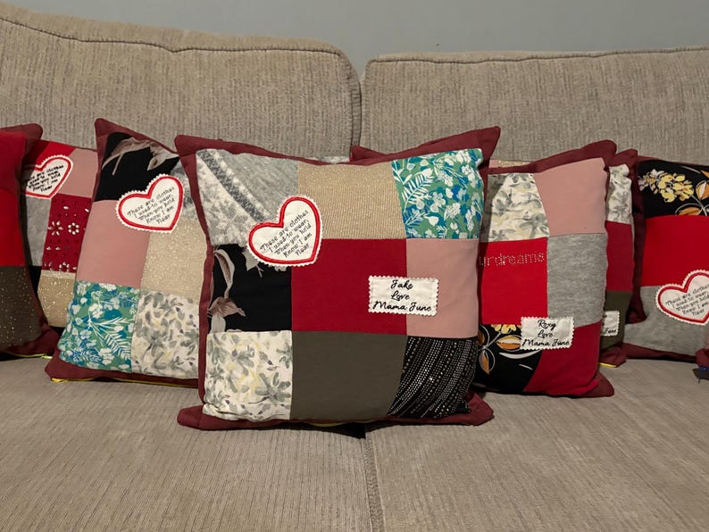 Pode incluir: Uma cole&ccedil;&atilde;o de almofadas de patchwork com uma variedade de padr&otilde;es e cores de tecido, incluindo florais, vermelho liso e tecidos estampados. Cada almofada tem uma borda vermelha escura e patches em forma de cora&ccedil;&atilde;o com texto bordado. Algumas almofadas t&ecirc;m patches retangulares adicionais com texto.
